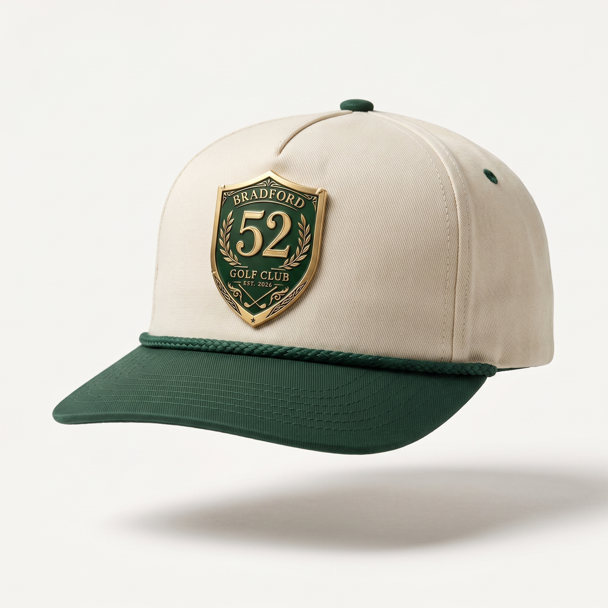 Mockup of the Bradford Golf Club Founders Rope Hat — cream five-panel rope cap, forest green brim and rope, with the club crest as a cast metal badge